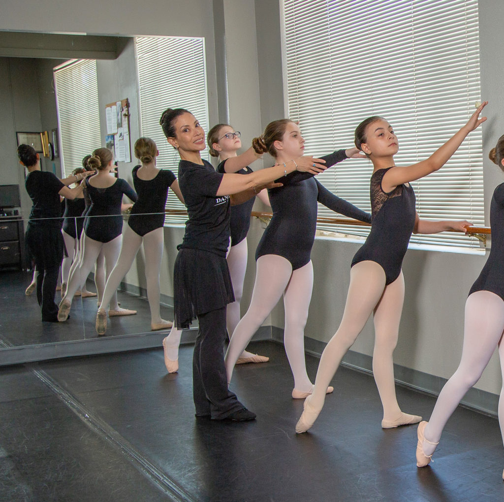 Ballet teacher and students lined up at the barre